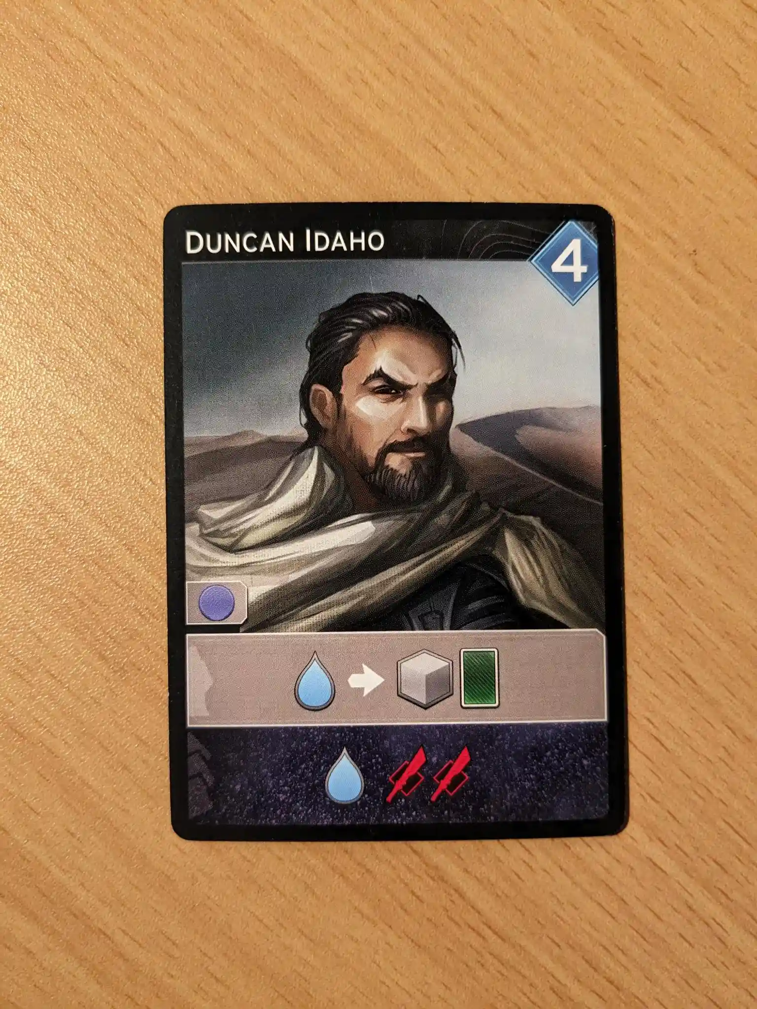 The Duncan Idaho card from Dune: Imperium. It has the symbol of a water drop with an arrow to a grey cube and green card. There is a second row with a water drop and two sword icons.